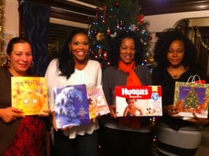 Four women posing with their gifts at a holiday event
