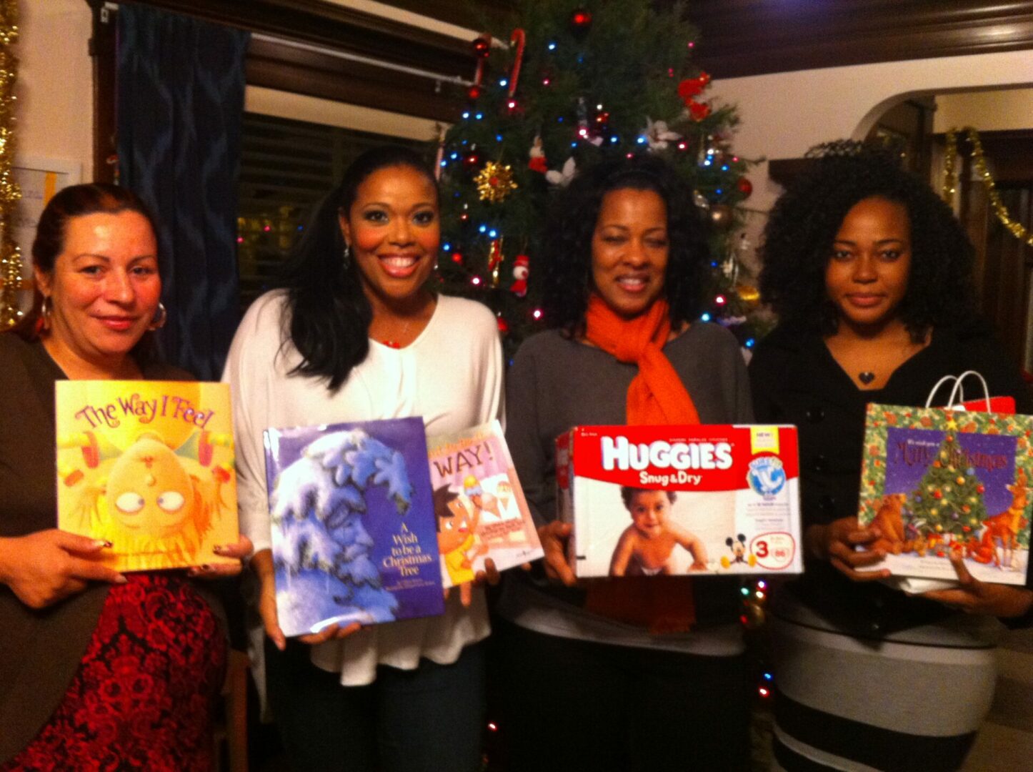 Four women posing with their gifts at a holiday event